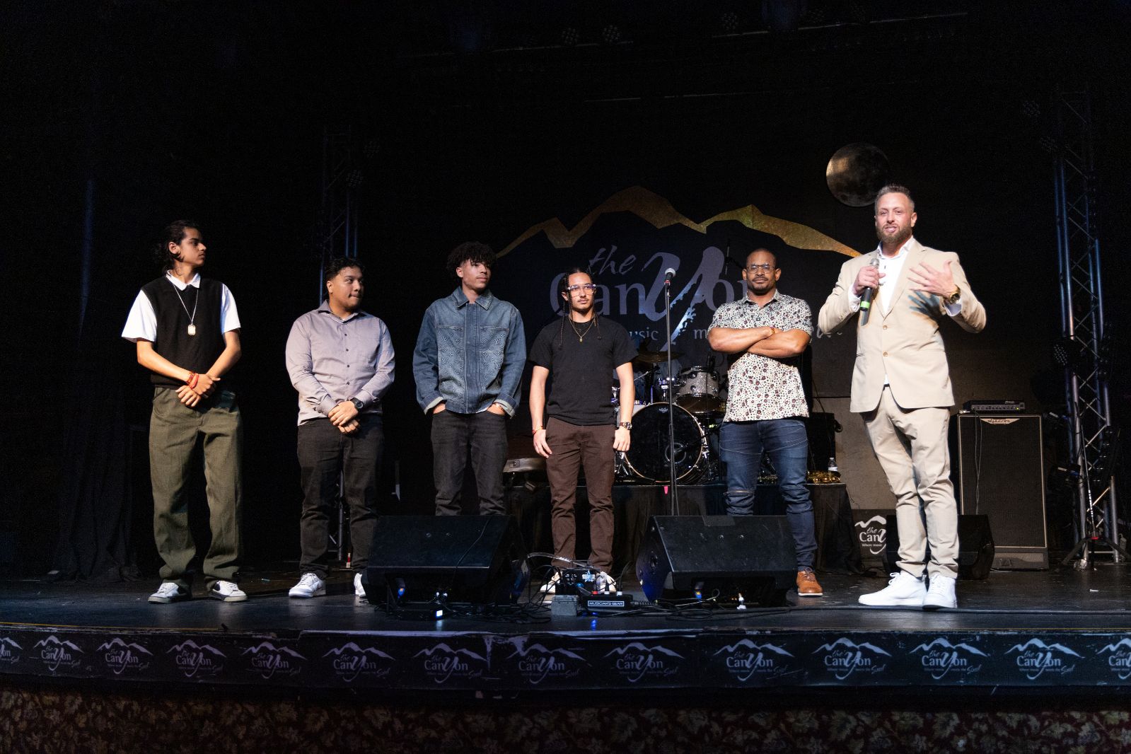 Güerote on stage at The Canyon with five certified Coaches — Warriors of the Compass commissioned in front of their community
