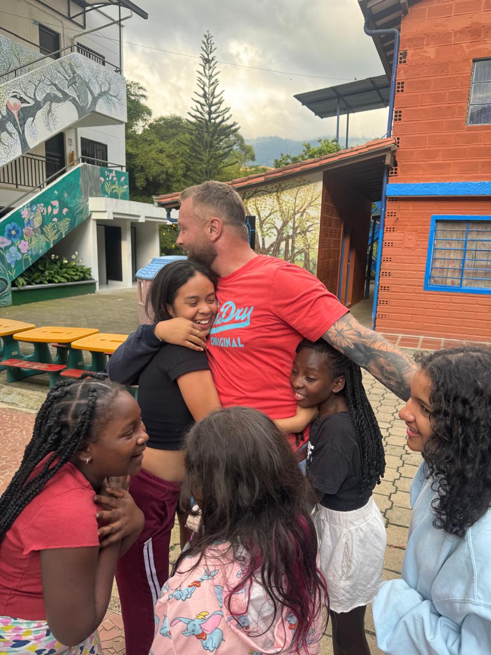 Güerote in red shirt hugging the kids at the Casa Hogar — the warriors he walks with every day